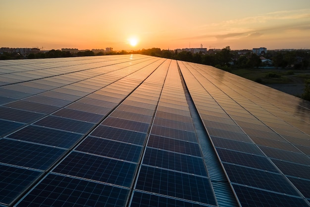 Paneles solares fotovoltaicos azules montados en el techo del edificio para producir electricidad ecológica limpia al atardecer. Producción de concepto de energía renovable.