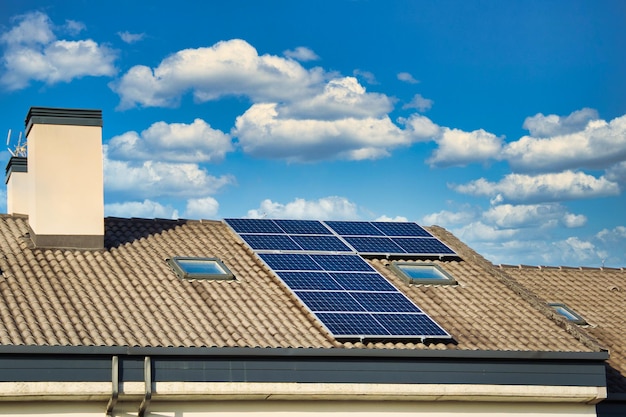 Paneles solares en el techo de las casas con cielo azul nublado en el fondo.