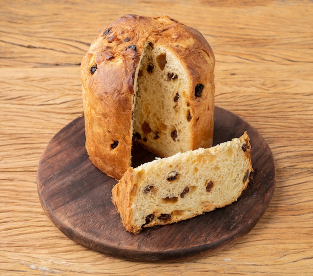 Panetone de bolo de frutas de Natal italiano tradicional com uma fatia em uma placa de madeira.