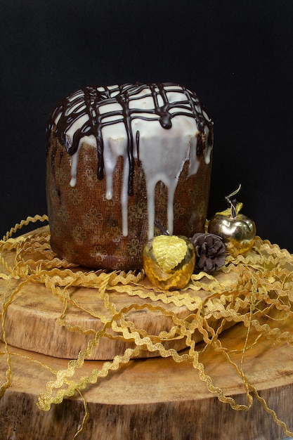 Panetone em uma mesa de madeira com fundo preto cercado por enfeites de Natal