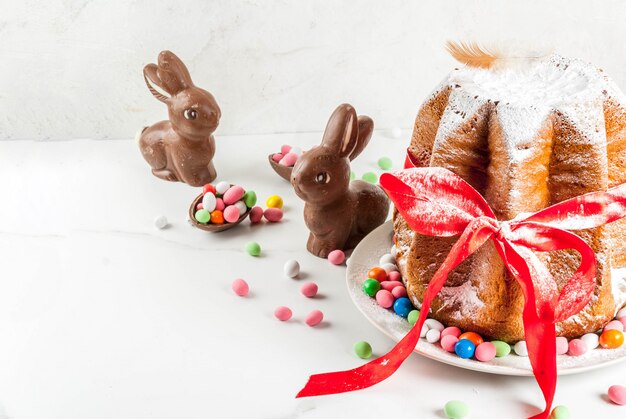 Panetone pandoro com fita vermelha festiva, coelhos da páscoa e decorações de ovos doces