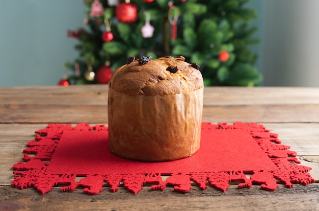 Panettone en la alfombra roja sobre una mesa de madera con un árbol de Navidad en el espacio de copia de fondo