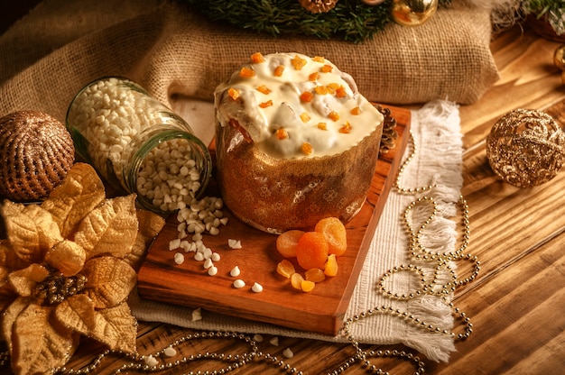 Panettone de chocolate blanco con albaricoque seco sobre mesa de madera con adornos navideños