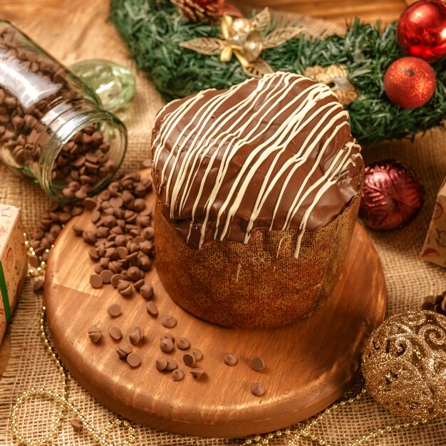 Foto panettone de chocolate sobre mesa de madera con adornos navideños