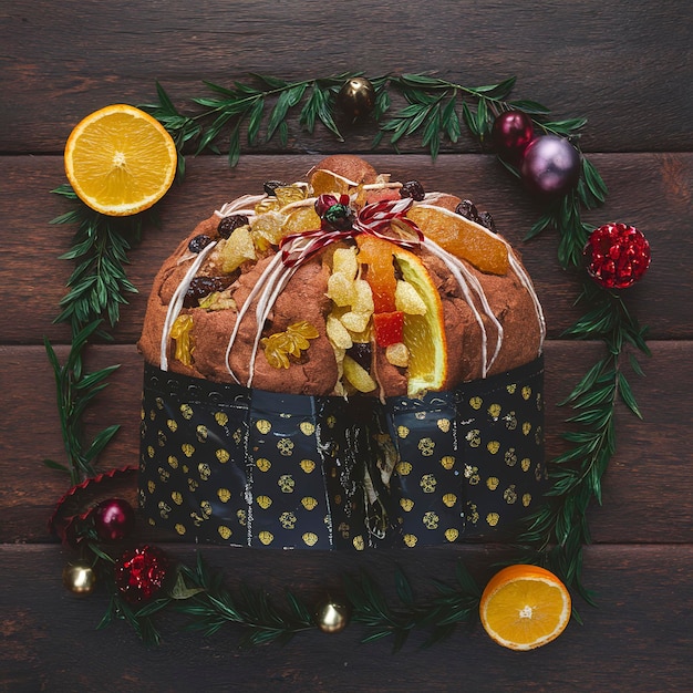 Panettone com passas confitadas de laranja de frutas e decoração de Natal em fundo de madeira