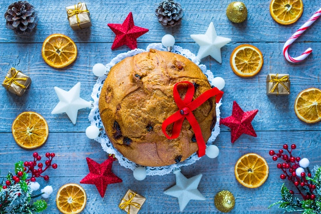 Panettone con fruta y decoración navideña sobre un fondo de madera