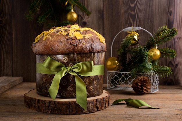 Panettone italiano tradicional de pastel de navidad con lazo verde y decoración festiva en madera rústica