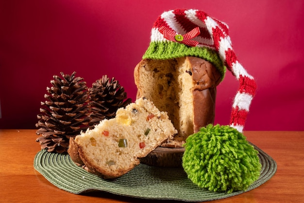 Foto panettone italienisches süßes mit weihnachtsmütterhut auf holztisch und rotem hintergrund