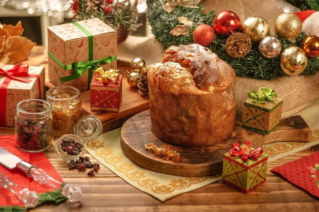 Panettone, Rosinen und kandierte Obstwürfel auf Holzschneidebrett mit Weihnachtsschmuck