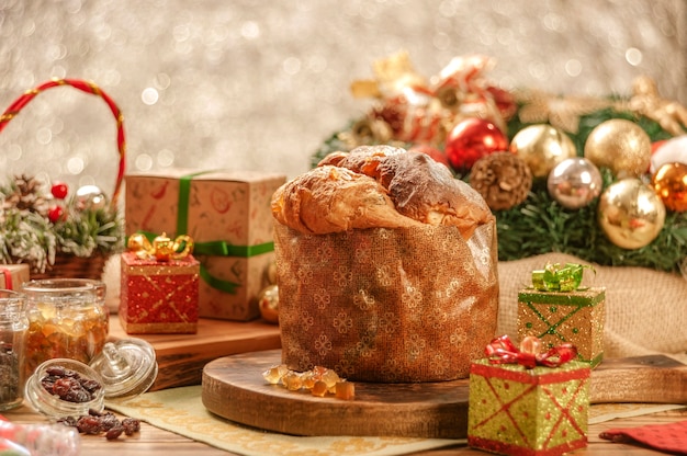 Panettone, Rosinen und kandierte Obstwürfel auf Holzschneidebrett mit Weihnachtsschmuck