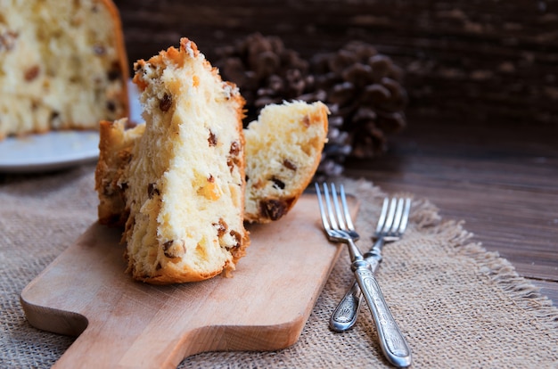 Foto panettone, traditioneller italienischer weihnachtskuchen auf rustikalem hintergrund mit weinlesegabel. speicherplatz kopieren.