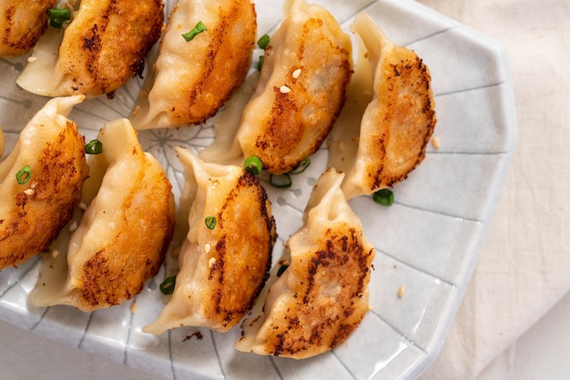 Panfried gyoza dumpling jiaozi en un plato con salsa de soja sobre fondo blanco de mesa