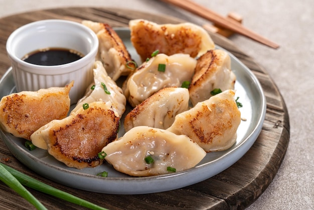 Panfried gyoza dumpling jiaozi en un plato con salsa de soja sobre fondo de mesa gris