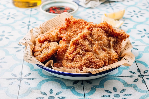 Panierte gebratene Tintenfischkoteletts mit pikanter Sauce und Zitrone