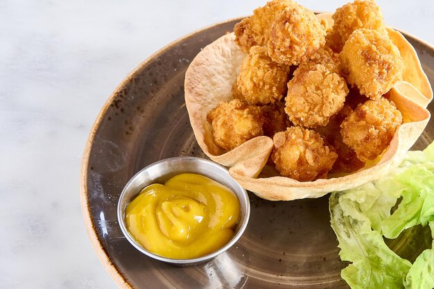 Foto panierte hähnchenbällchen mit senfsauce und salat