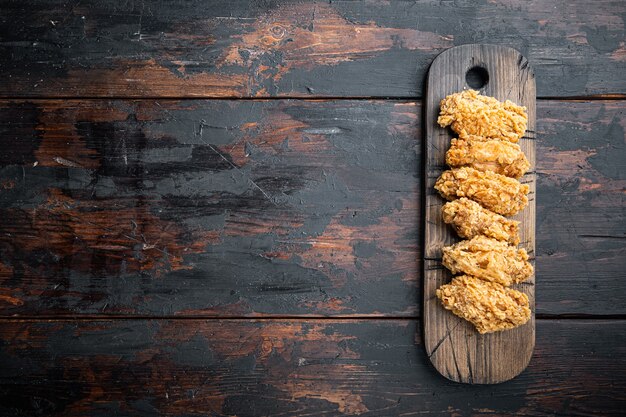 Foto panierte hühnerflügelschnitte auf dunklem holztisch, draufsicht.