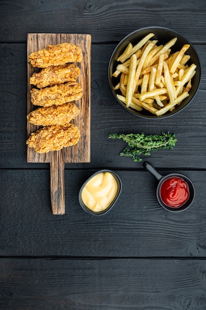 Panierte Hühnerflügelschnitte auf schwarzem Holztisch, flach liegend, mit Kopierraum.