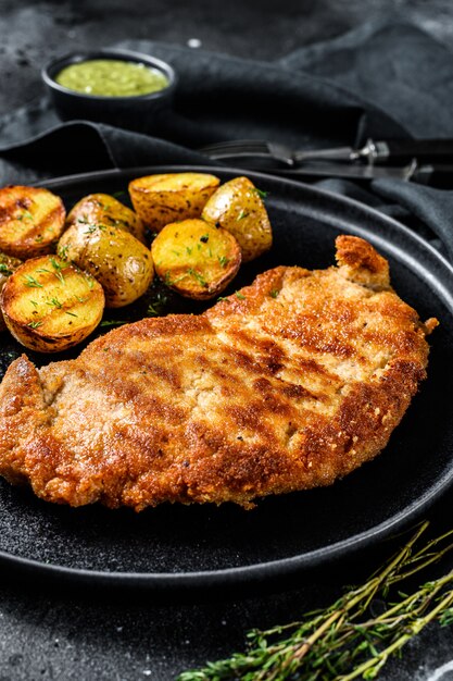 Paniertes deutsches weiner schnitzel mit kartoffeln. Schwarzer Hintergrund. Draufsicht