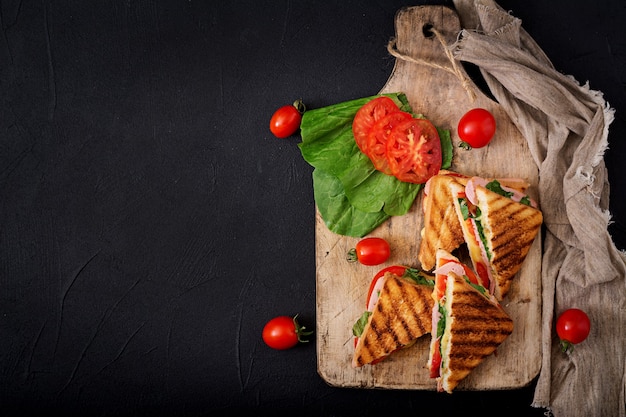 Panini do sanduíche de clube com presunto, tomate, queijo e manjericão. lay plana. vista do topo