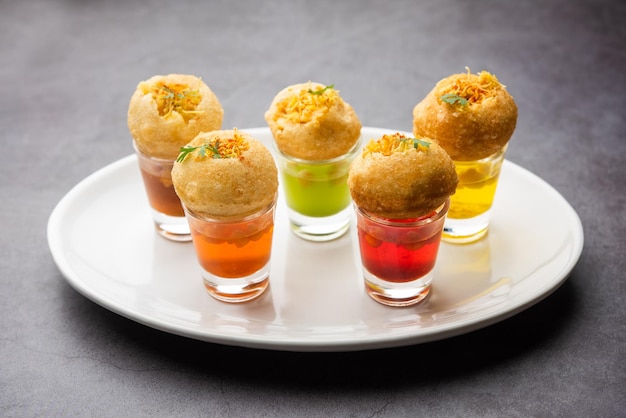 Panipuri-Shot oder Golgappa-Shots mit verschiedenen Wasseraromen, serviert in kleinen Gläsern mit gefülltem Puri-Indischer Vorspeise-Snack