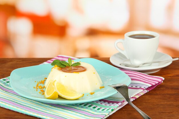 Foto panna cotta con cáscara de naranja y salsa de caramelo sobre un fondo de madera de color