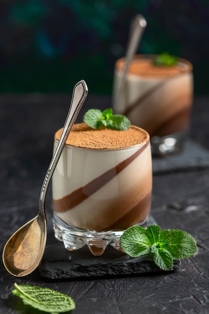 Foto panna cotta con chocolate y vainilla en vasos de vidrio en un soporte de pizarra