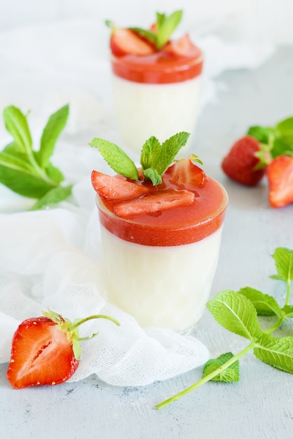 Panna cotta de deliciosa sobremesa italiana com molho de morango, morangos e folhas de hortelã fresca