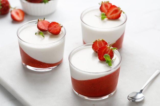 Panna cotta con fresa en frascos de vidrio decorados con bayas frescas y postre italiano de menta