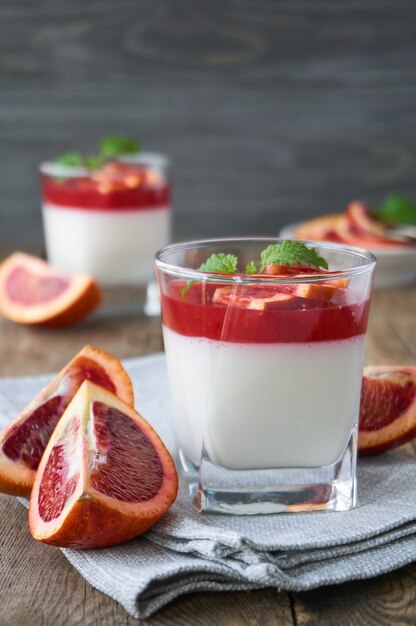 Panna cotta con gelatina de naranja roja sobre una mesa de madera