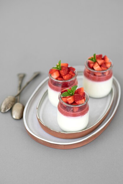 Panna cotta de postre italiano con gelatina de frutas y trozos frescos de fresas en gris