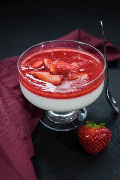 Foto panna cotta con salsa de fresa y bayas de fresa en un bol sobre fondo negro