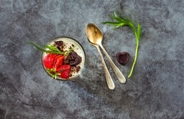 Panna cotta sobremesa com morangos e chocolate, estragão verde em cinza vintage