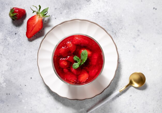 Panna cotta vegan com molho de morango e hortelã em fundo cinza