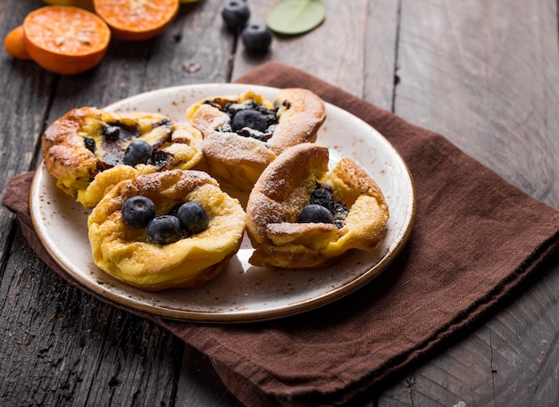 Pannukakku oder dänischer Pfannkuchen mit Beeren, die mit Zuckerpulver bedeckt sind