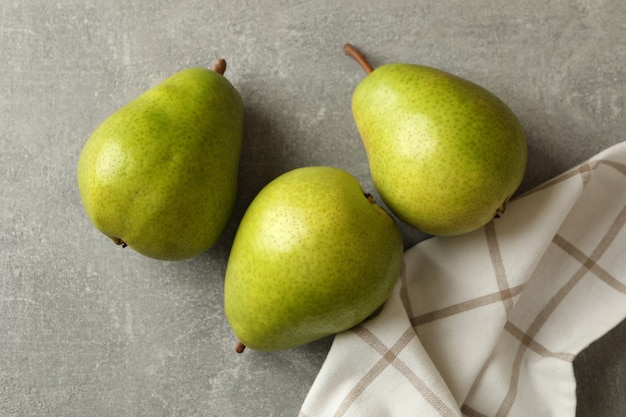 Paño de cocina y peras verdes sobre gris