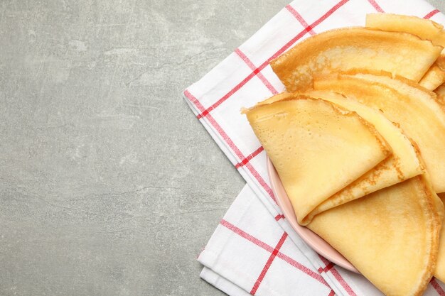 Paño de cocina con plato de tortitas finas en mesa gris