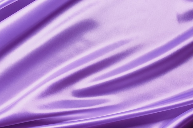 Foto pano de seda de cetim roxo abstrato para plano de fundo, cortina de tecido têxtil com dobras onduladas vinco. com ondas suaves, balançando ao vento.