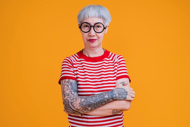 Pano em forma de cabelo grisalho feminino asiático sênior com tatuagem braço em pé gesto com expressão confiante positiva mulher asiática antiga veste camiseta vermelha estilo de vida despreocupado felicidade idade de pensão