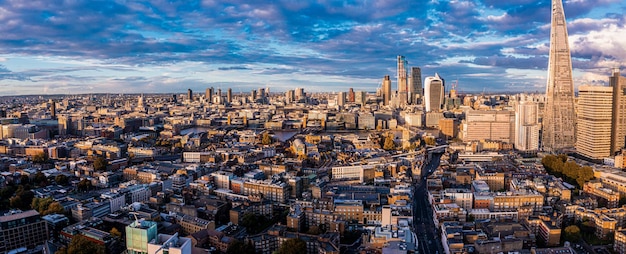 Panorama aéreo del distrito financiero de la ciudad de Londres con muchos rascacielos icónicos cerca del río Támesis al atardecer.