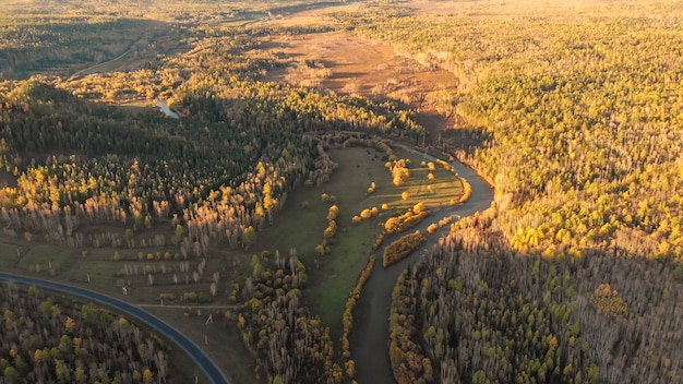 Panorama aéreo de drone sobre un río, bosque de otoño, colina y carretera. Paisaje rural de la naturaleza del otoño en la puesta del sol desde la vista de pájaro.