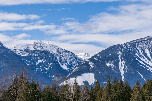 Panorama de altas montañas cubiertas de nieve cielo azul nublado columbia británica canadá