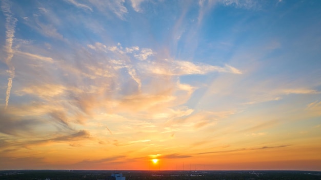 Panorama del atardecer con sol dorado y nubes de gris blanco y violeta bajo el cielo azul