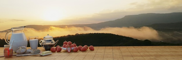 Foto panorama café da manhã leite fresco café em um copo e uma cafeteira pão de manteiga em uma tábua de cortar de madeira muitos morangos frescos montanha pela manhã com névoa e o sol brilha renderização 3d