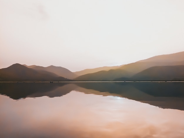 Foto panorama cênico do belo pôr do sol no lago com cadeias de montanhas na natureza de background.minimal.