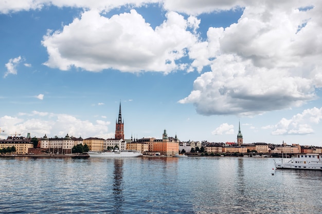 Panorama cênico do verão da arquitetura velha da cidade (gamla stan) em éstocolmo, suécia. vista da colina de monteliusvagen na ilha riddarholm e torre da igreja. lago malaren com céu azul, nuvens brancas.