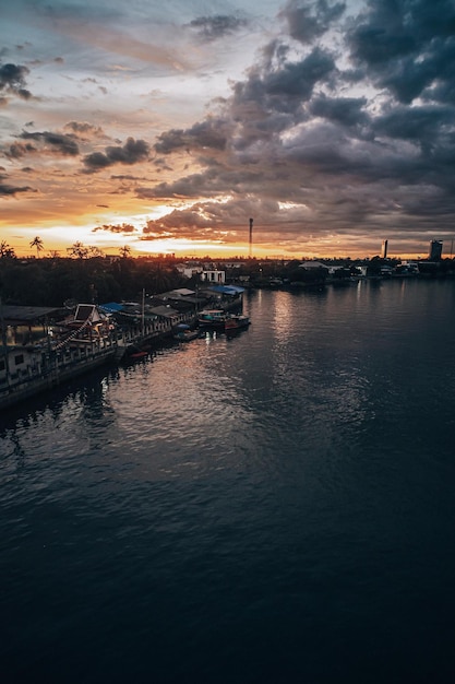 Panorama Cityscape ao pôr do sol com grande rio em primeiro plano e nuvens strom ao fundo na Tailândia