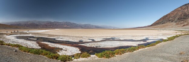 Panorama da área de bad water basin no vale da morte com alguns turistas caminhando pelas passarelas