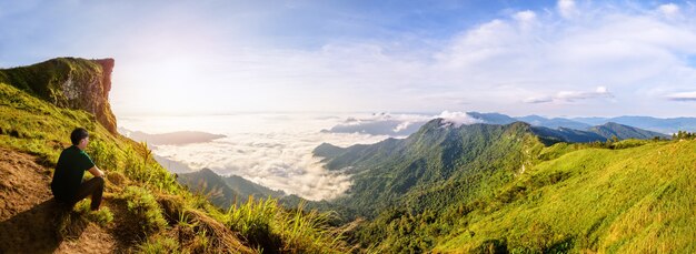 Panorama da natureza da bela paisagem, turistas do sexo masculino estão assistindo o nascer do sol no pico da montanha com neblina de nuvens de sol e céu claro no inverno no Parque Florestal de Phu Chi Fa, famosa atração de Chiang Rai, Tailândia