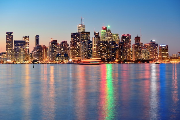 Panorama da paisagem urbana de Toronto ao entardecer sobre o lago com luz colorida.