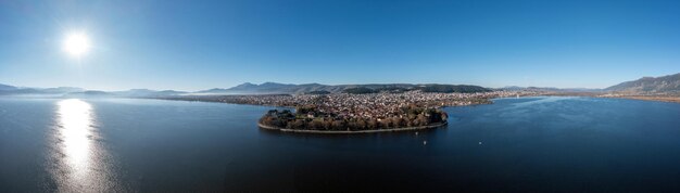 Panorama da vista aérea da cidade de Grécia Ioannina de Giannena e do céu azul do lago Pamvotis